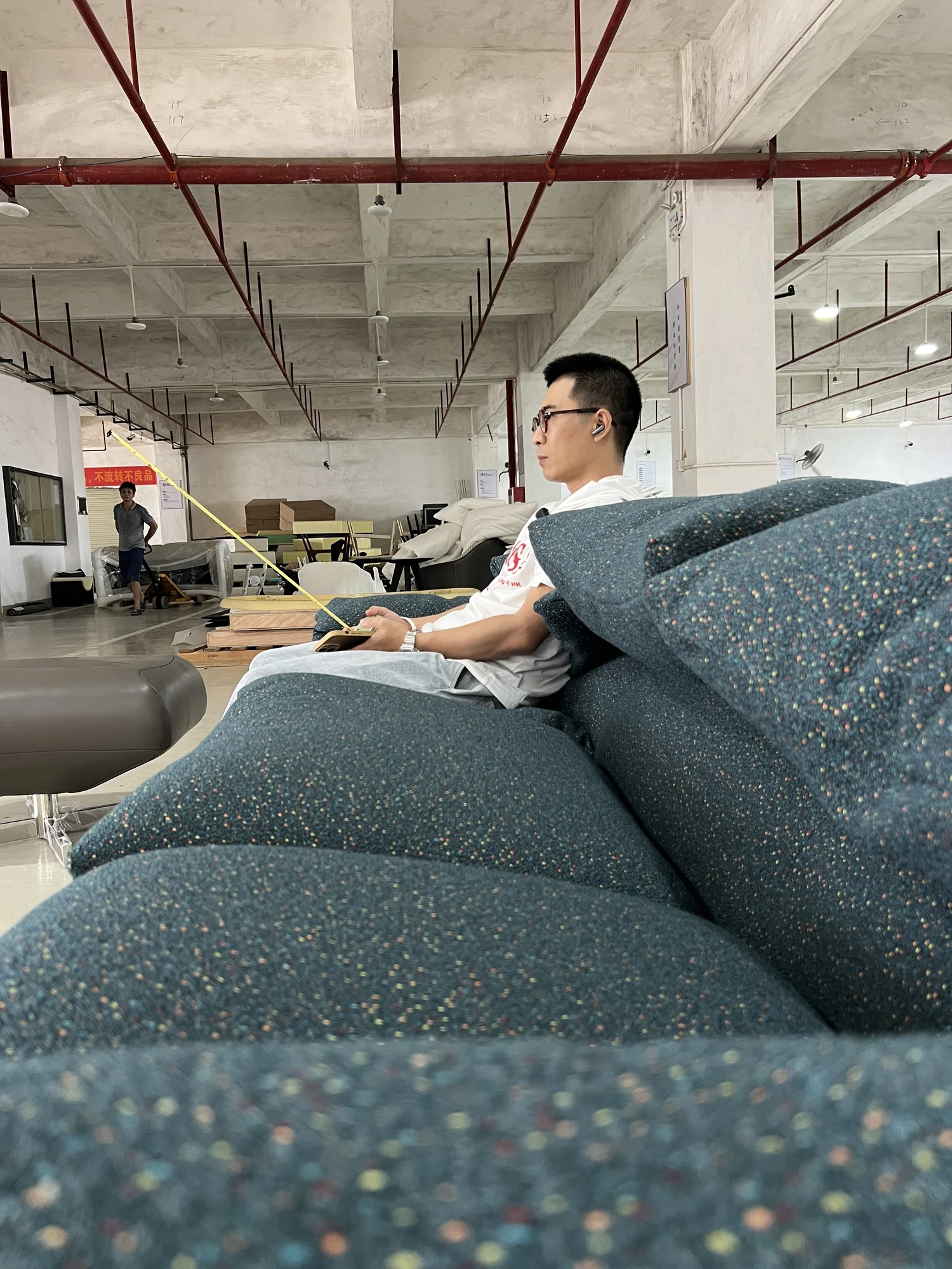 Worker upholstering a blue-green sofa inside a Foshan furniture factory