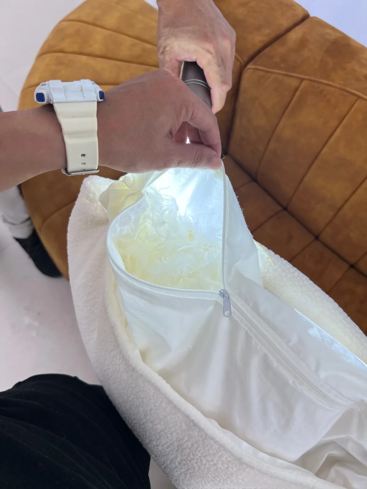 Inspector unzipping a boucle cushion cover with a torch to check the down and feather inner