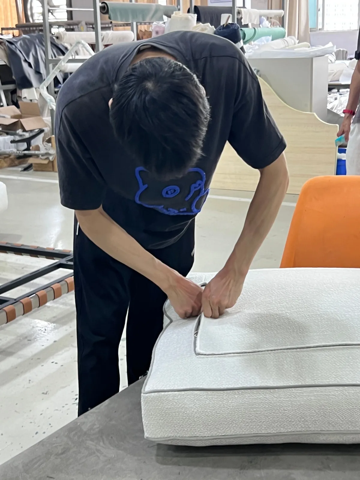 Upholsterer checking the grey piping and seam on a cream boucle seat cushion at the workbench