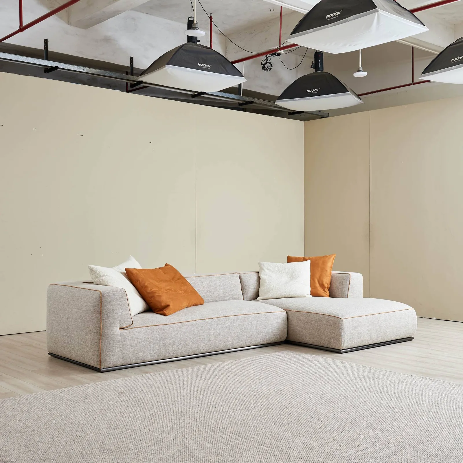 Custom grey linen sectional with a chaise and contrast piping photographed in a Foshan studio