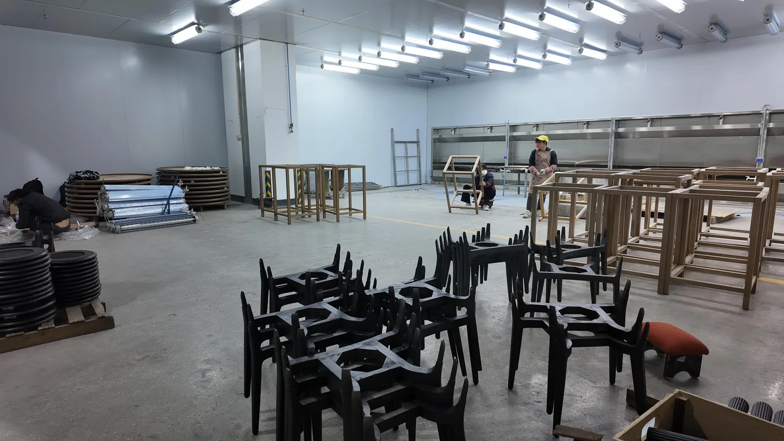 Rows of bare timber chair frames on a factory floor before upholstery