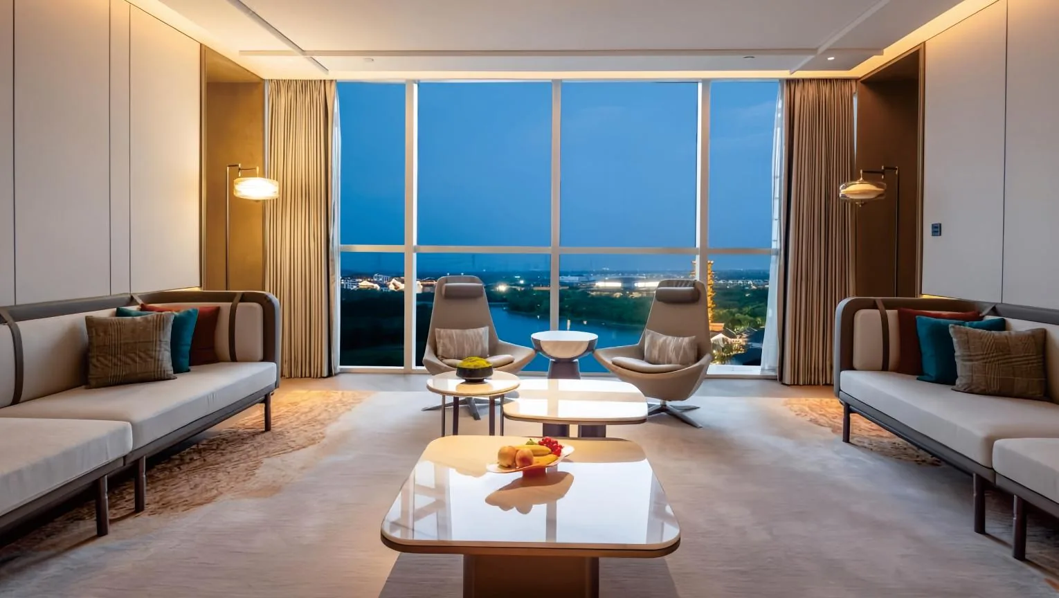 Meeting lounge with tables and upholstered chairs by tall windows