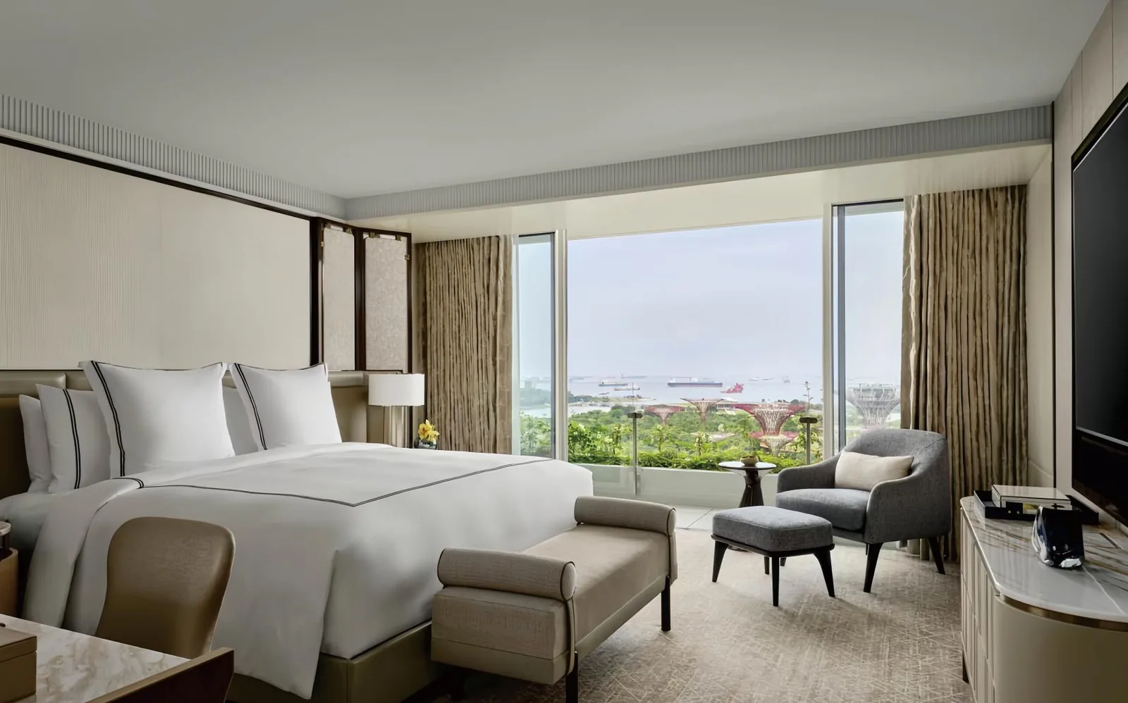 Hotel guestroom with upholstered lounge seating, casegoods and bed, furnished by a partner hospitality factory