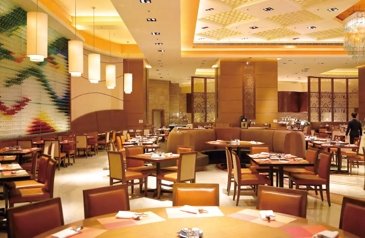 Hotel restaurant with banquette seating and dining chairs under a patterned ceiling