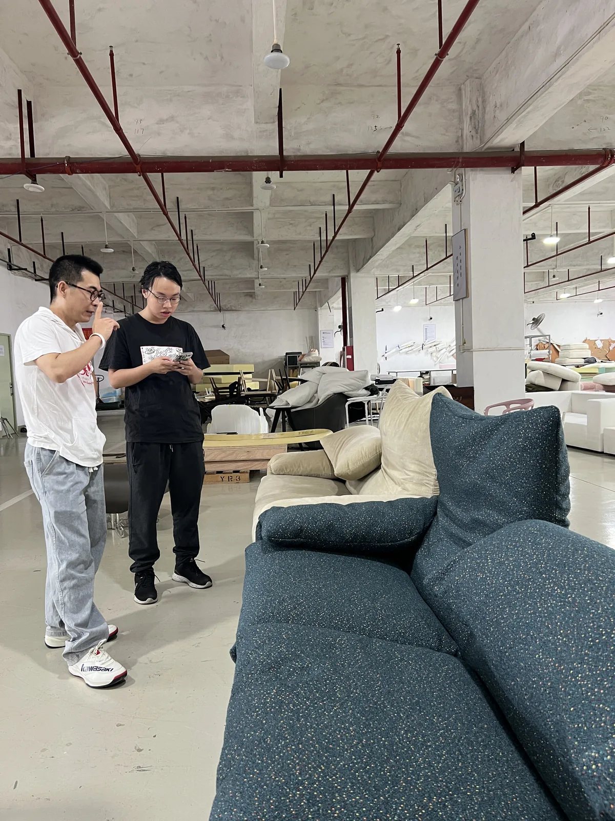 Inspector checking a sofa frame on a factory floor in Foshan
