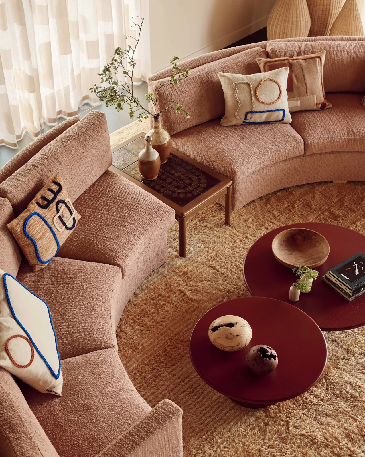 Reference image: curved terracotta sofa with round stone tables