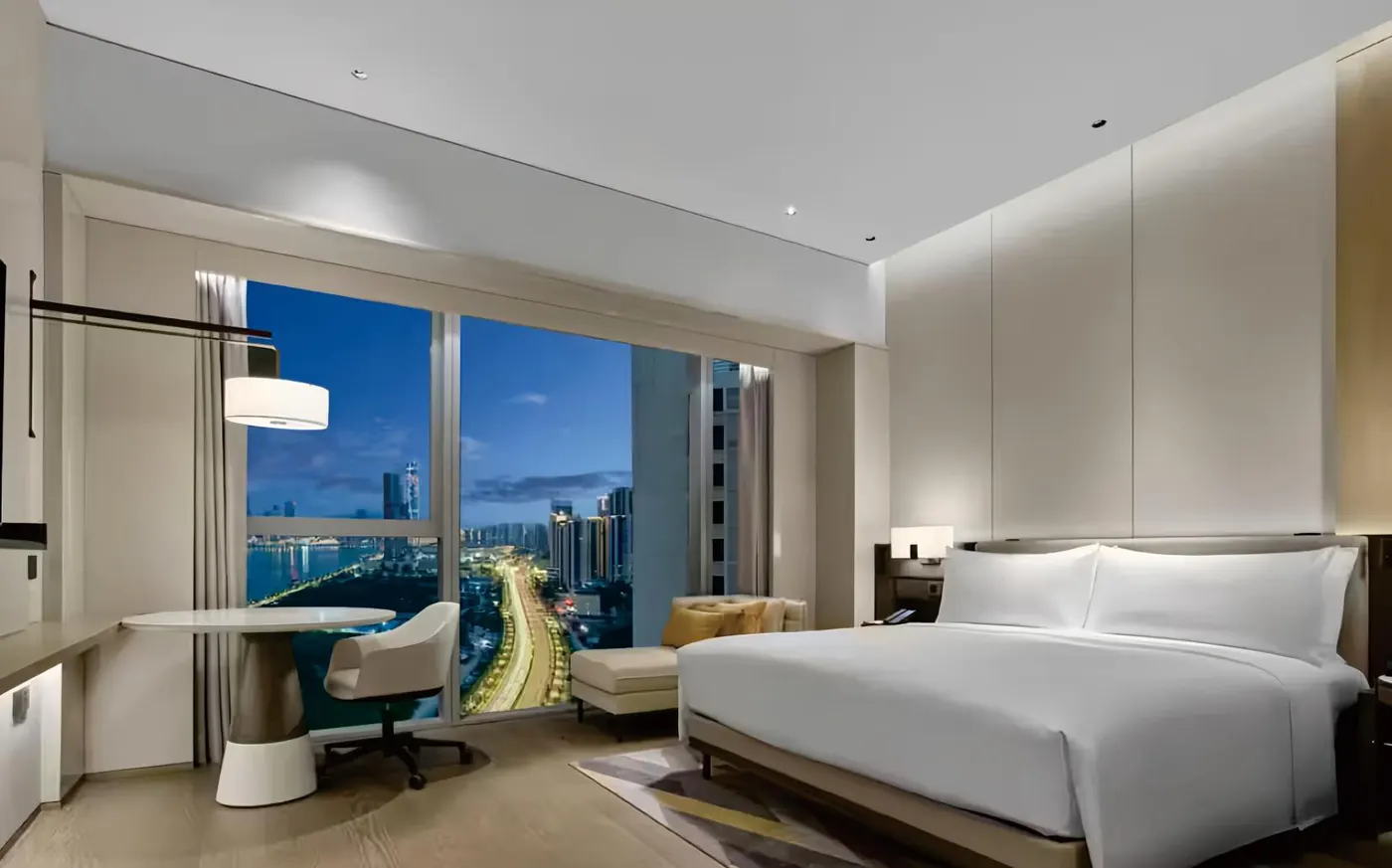 Five-star king guestroom with desk, lounge chair and bench at night