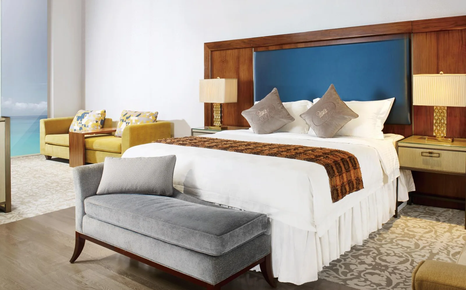 Hotel guestroom with blue headboard panel and timber casegoods