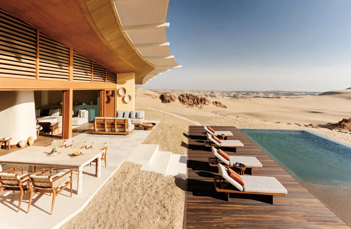 Desert resort pool deck with timber sun loungers and shaded lounge beside the water
