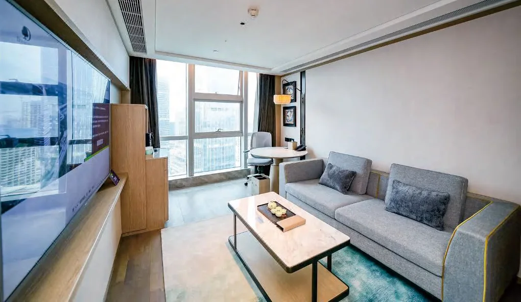 Hotel suite lounge with grey sofa and TV wall