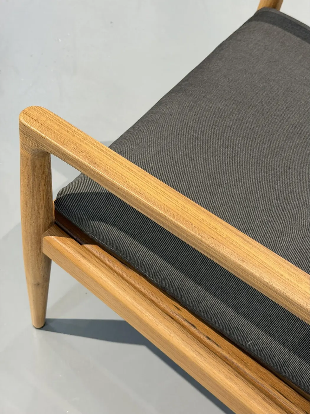 Close-up of a teak outdoor chair frame joint and cushion edge