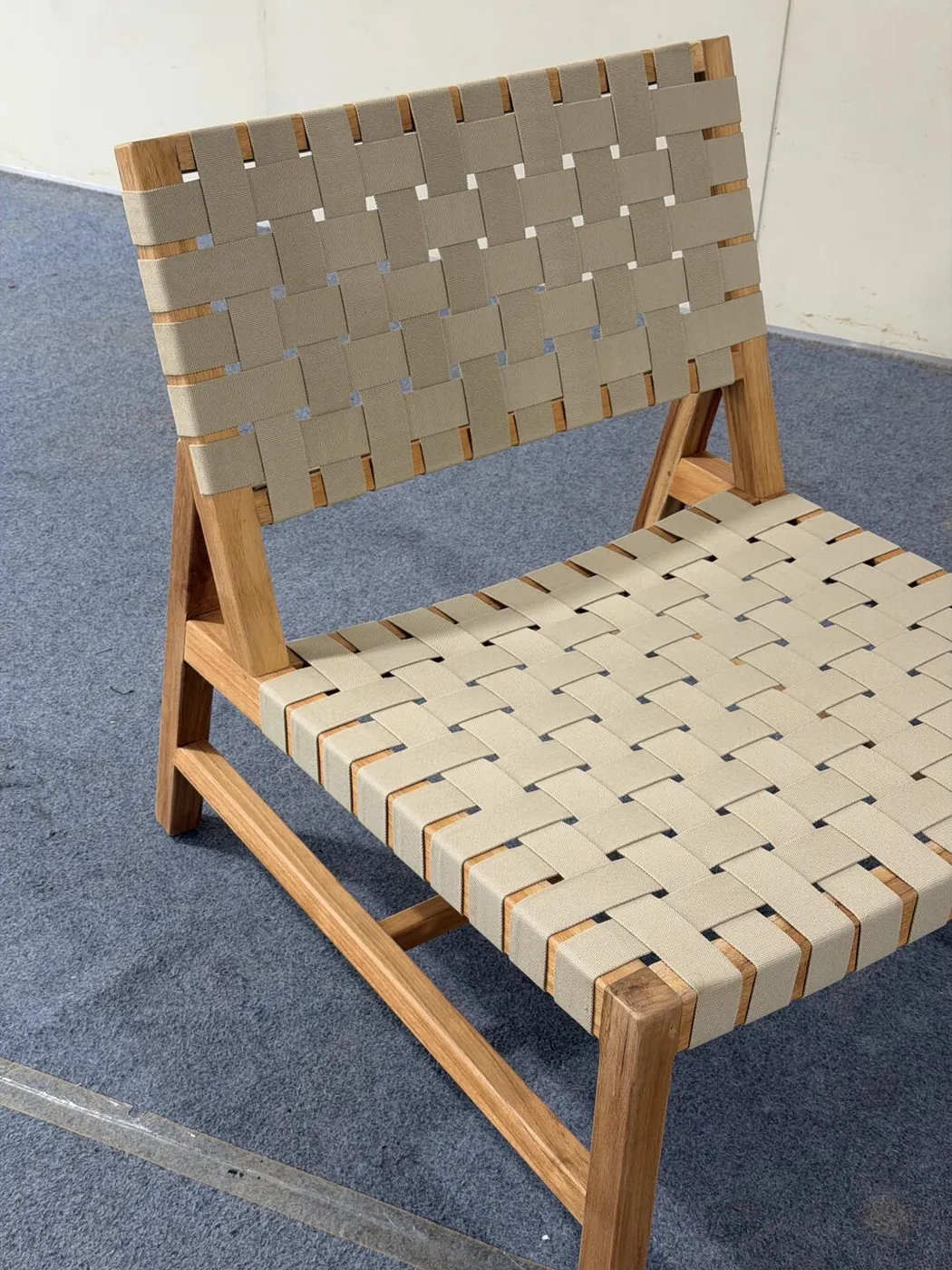 Close-up of woven webbing seat and back on a teak outdoor chair
