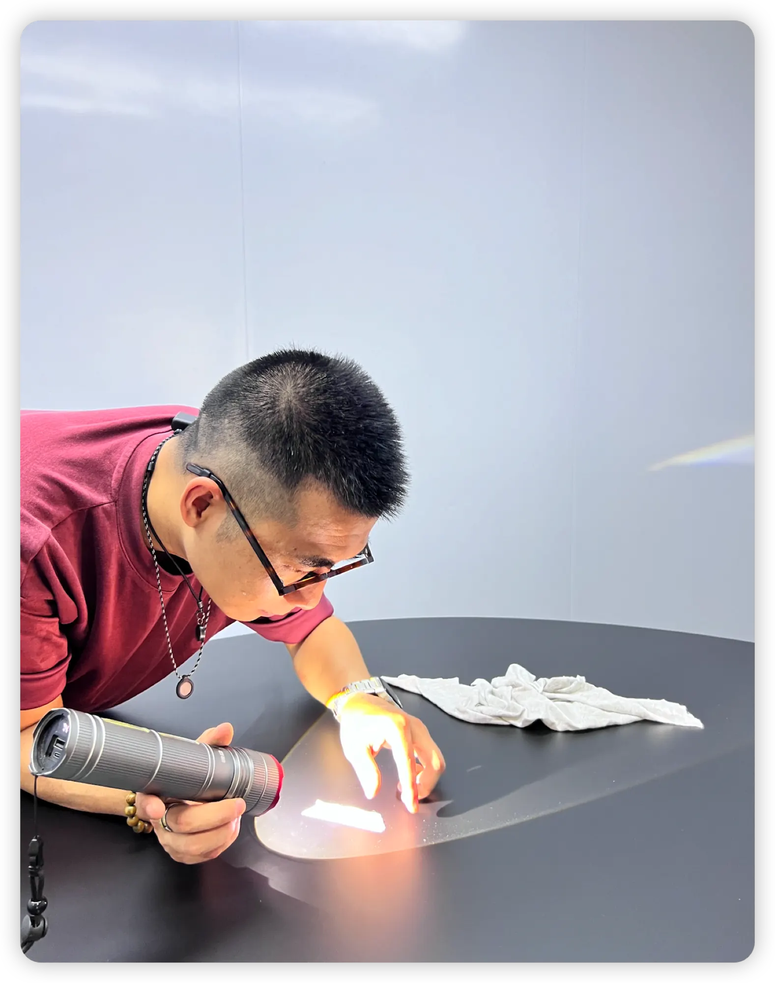 Inspector checking a dark table top under a flashlight during quality control