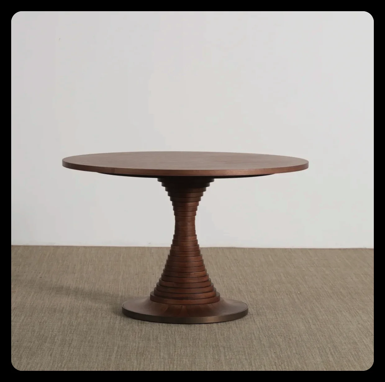 Round walnut dining table with a turned pedestal base