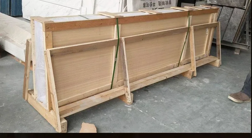 Stone table tops strapped upright on a timber A-frame inside an open crate