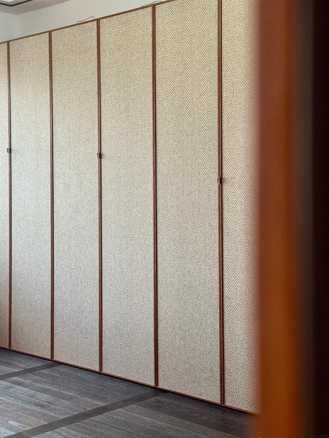 Floor-to-ceiling wardrobe fronts with a woven herringbone finish