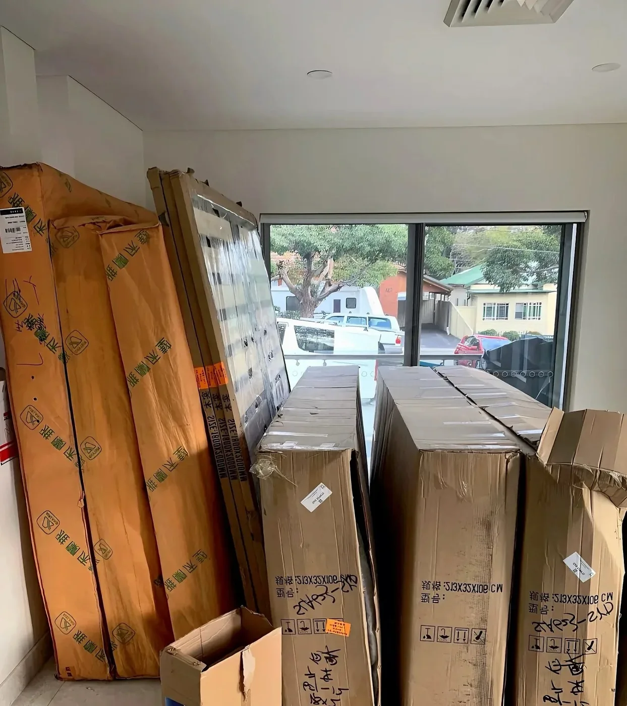 Tall flat-pack cartons and wrapped parts stacked inside a new Australian home on delivery day