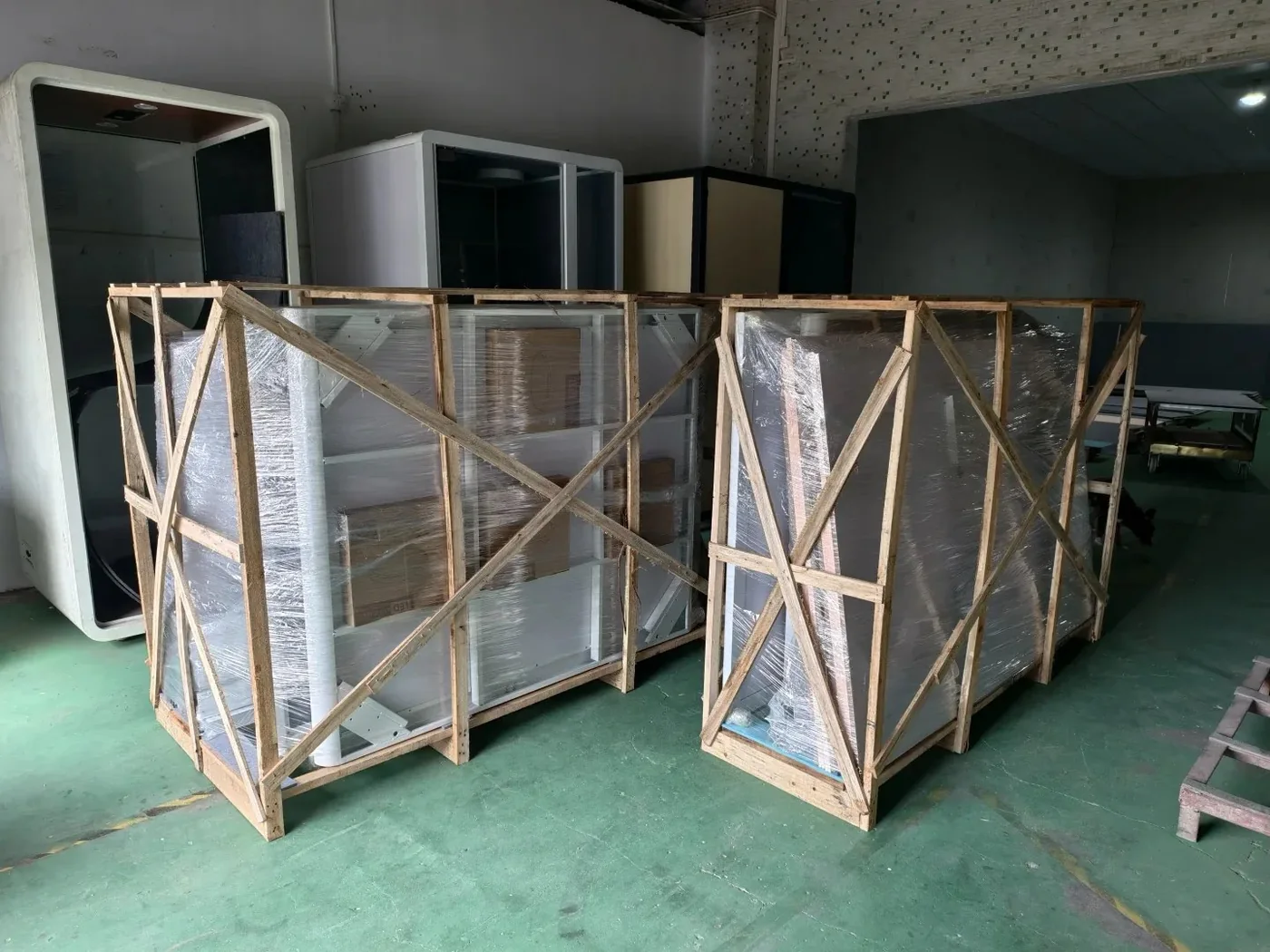 Two glass display cabinets wrapped in stretch film inside timber frames in a workshop in Panyu, Guangzhou