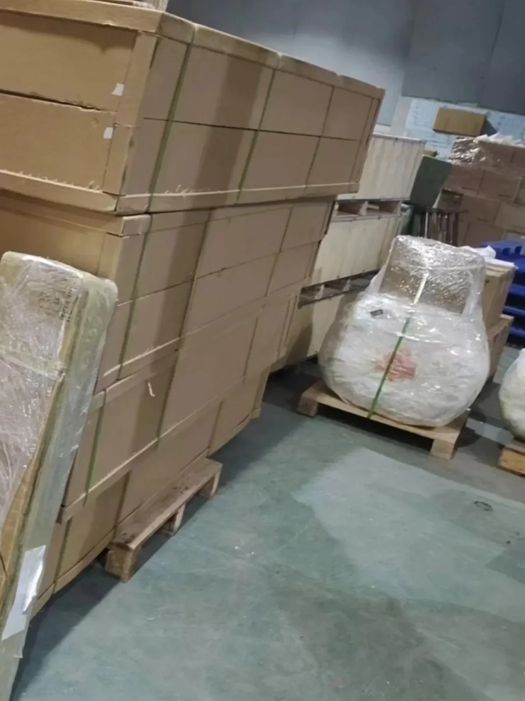 Large cartons strapped onto wooden pallets and a chair wrapped in bubble film in an export warehouse