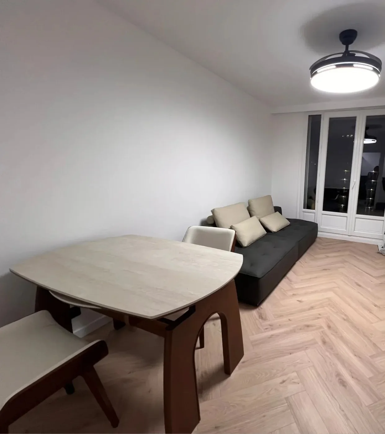 A French apartment living room with a sintered-stone dining table, chairs and dark sofa shipped from China