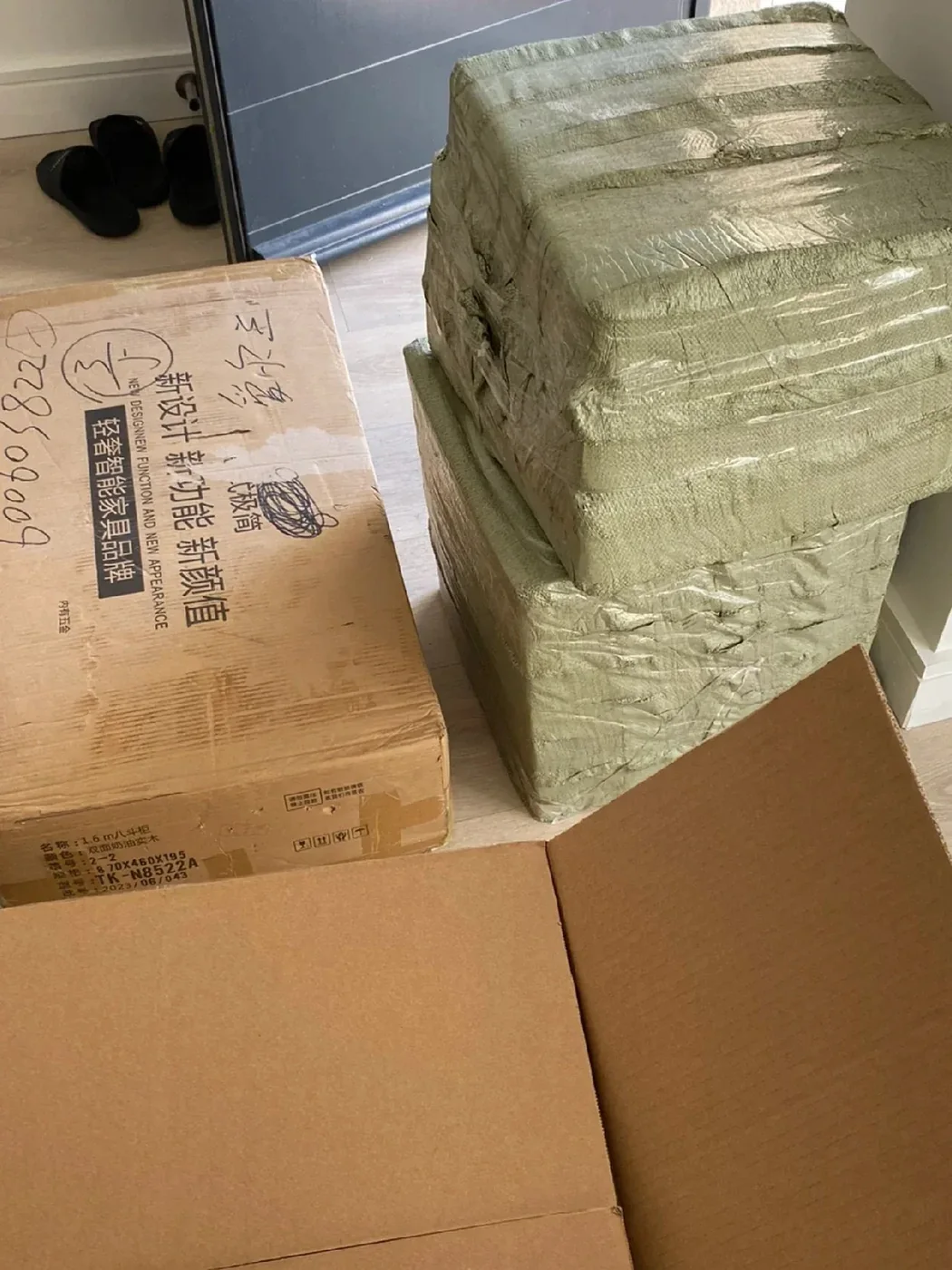 A just-arrived furniture carton and woven-bag parcels inside the front door of an Irish home