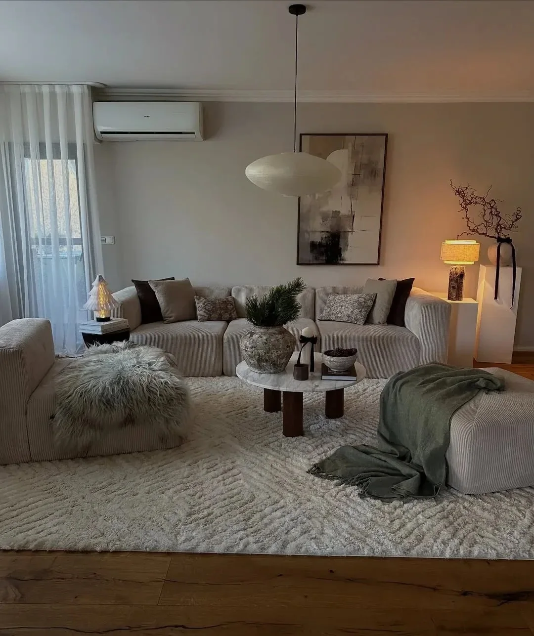 A UK living room with a corduroy modular sofa, round marble coffee table and ottoman