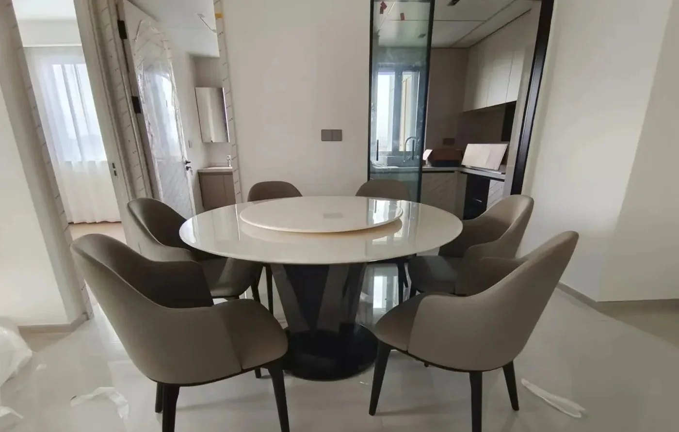 A round marble dining table and six lounge chairs set up in a US home still under renovation