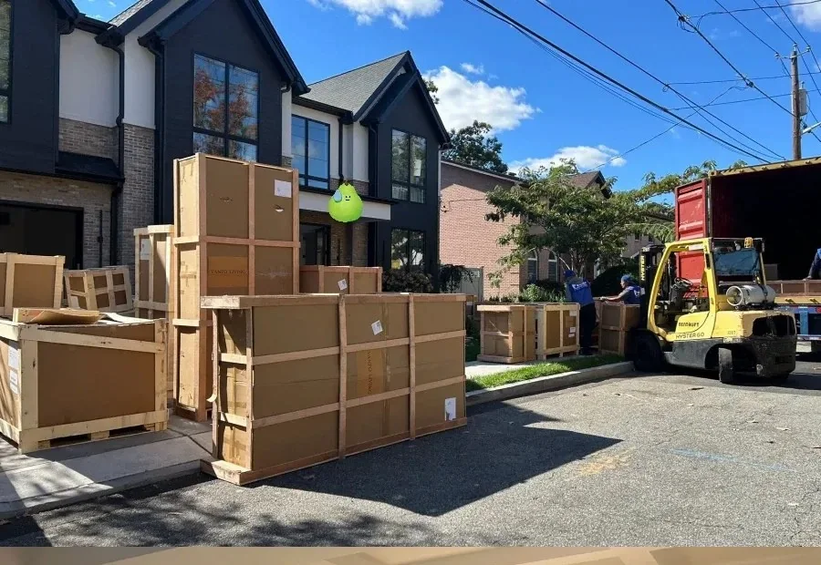 Crates and wrapped furniture staged on the street outside a US home while a forklift works off the back of the truck