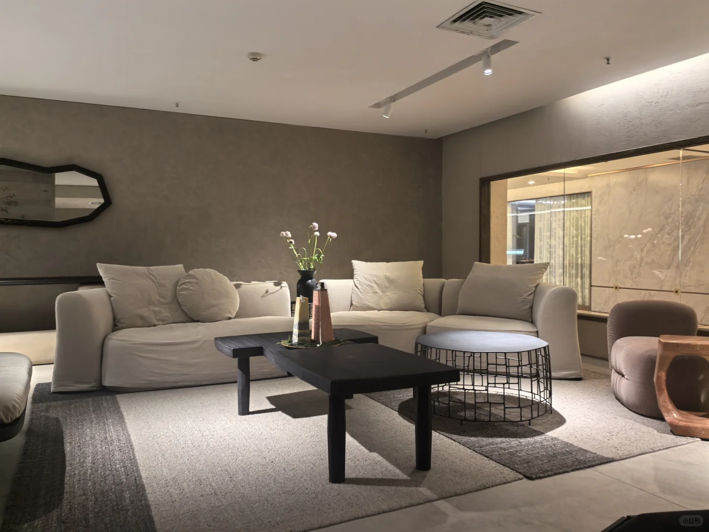 Pale sofas, dark sculptural coffee tables and a rounded side chair in a warm neutral DAaZ room setting.