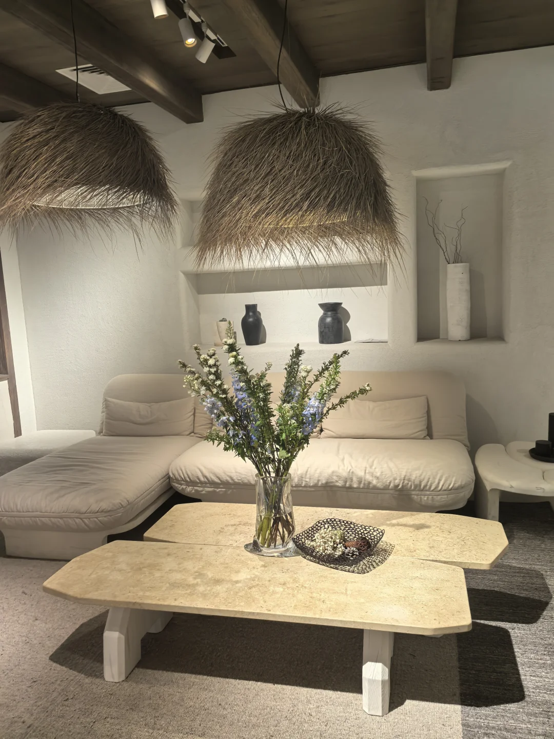 Pale seating, a low timber table and two woven pendant shades in the DAaZ furniture display.