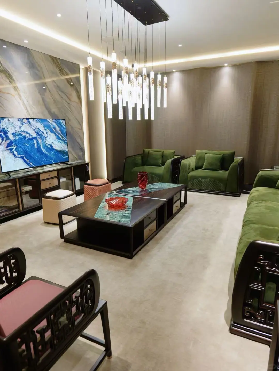 Green upholstered Chinese-style seating and dark-framed tables beneath a cluster of slender pendant lights.