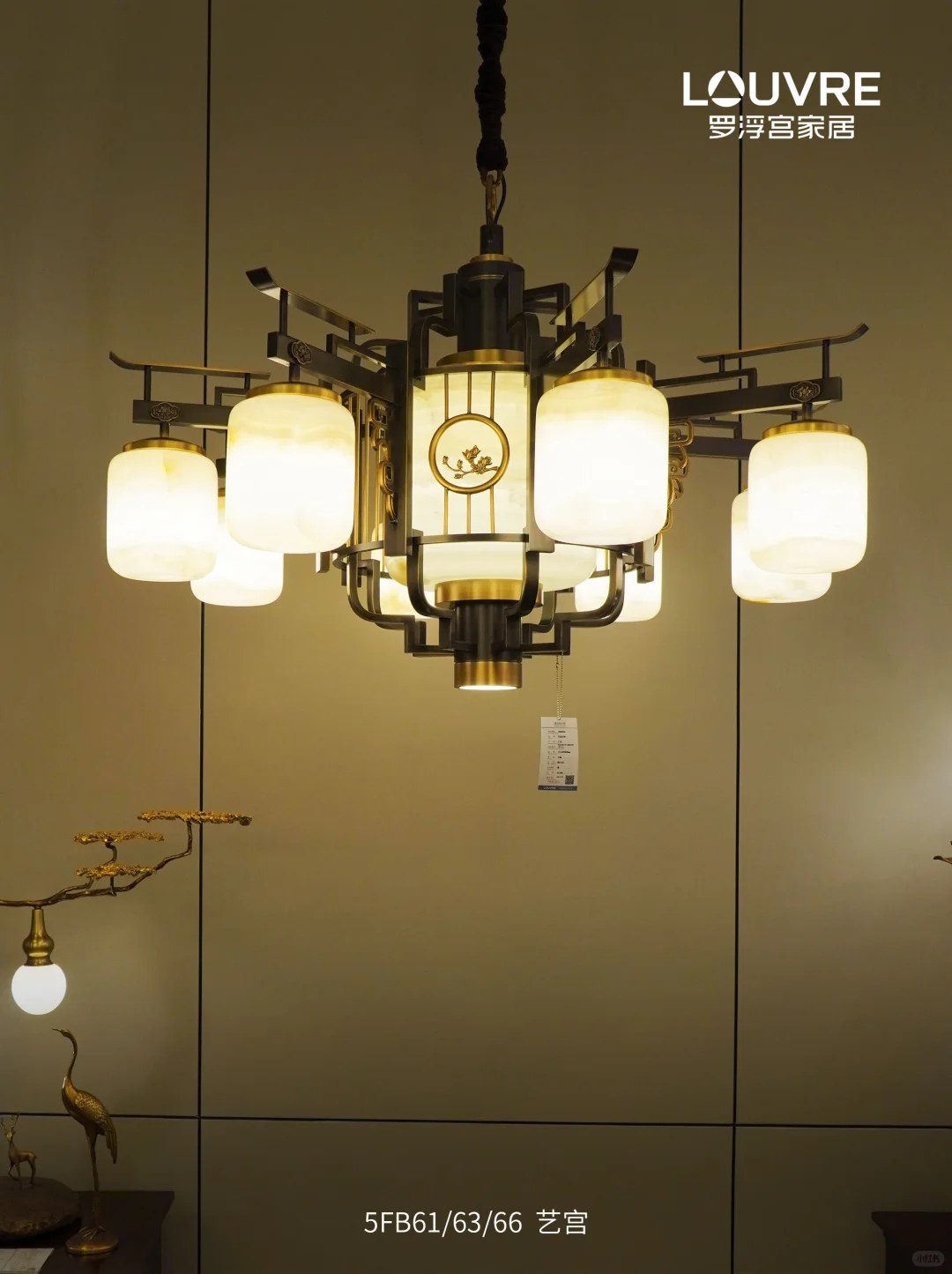 A dark-framed multi-arm pendant with glowing pale shades against a warm wall.
