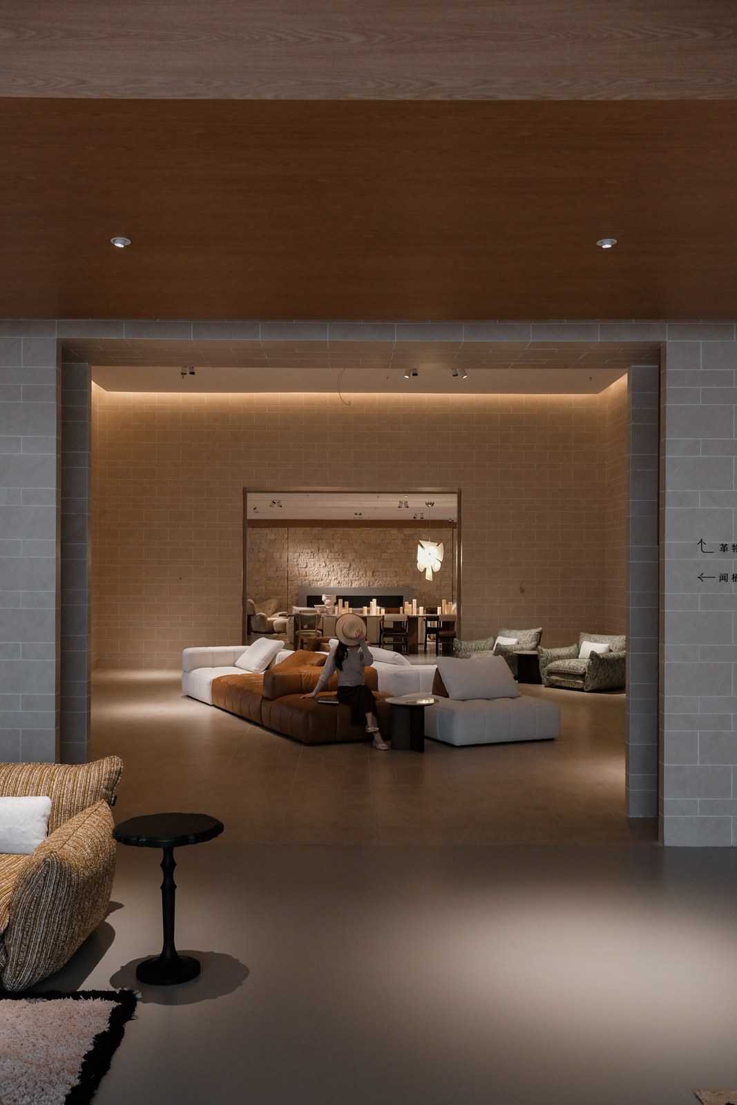 Layered showroom openings with modular sofas, lounge chairs and a dining table in the distance.