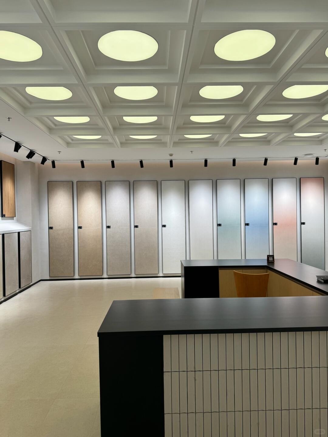 Tall neutral and pastel sample panels behind a dark-topped, vertically tiled counter.