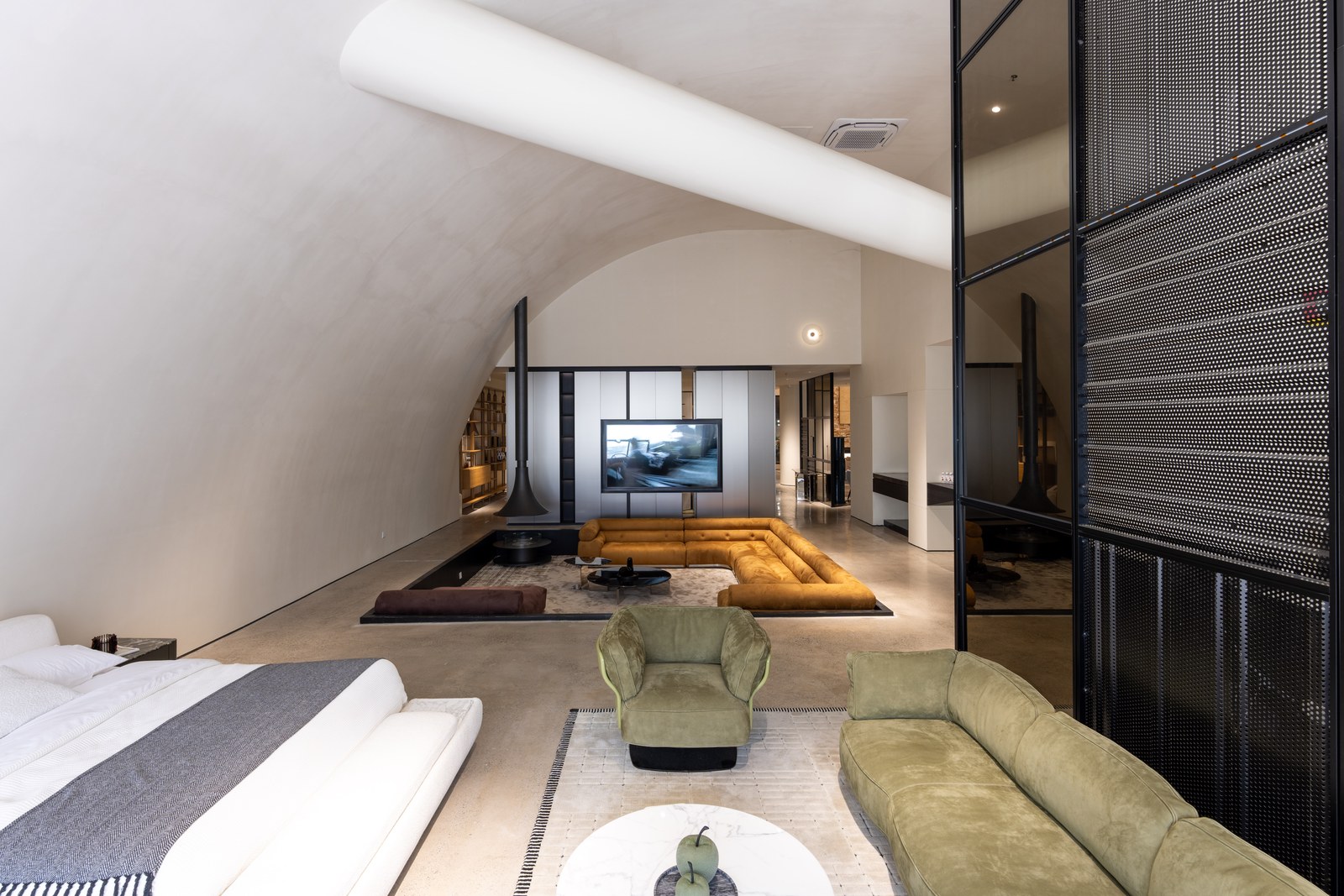 Layered furniture displays beneath a curved ceiling, including an ochre sectional and pale green seating.