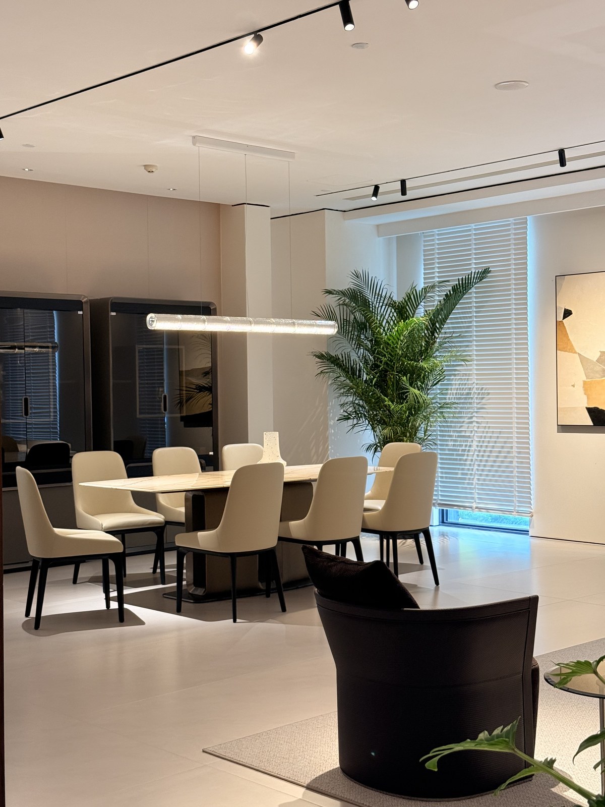 Dining table and cream upholstered chairs beneath a narrow pendant light.