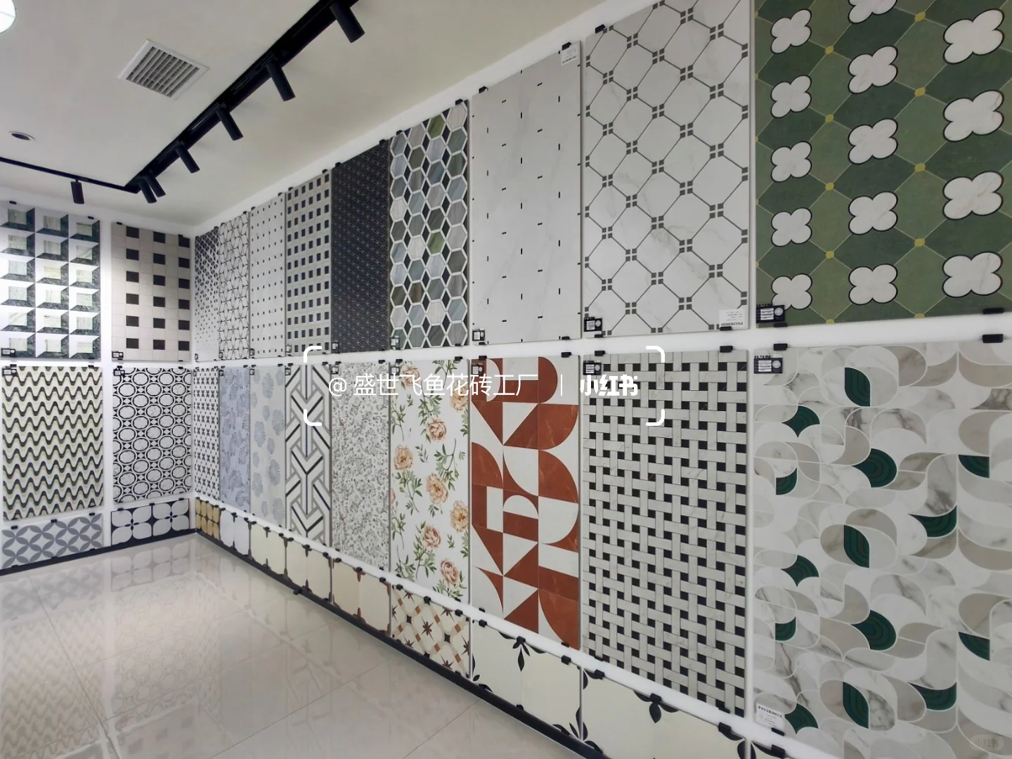 Two showroom walls covered with large sample boards of geometric and floral tile layouts.