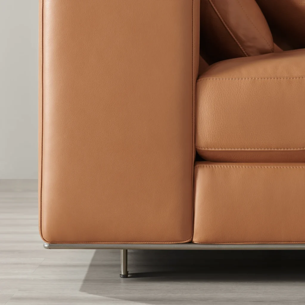 Close-up of a tan leather sofa arm and base with a black metal leg