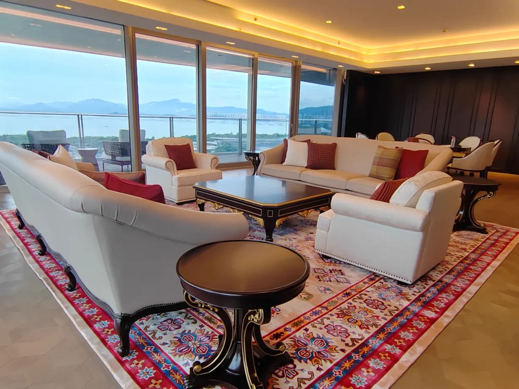 Formal living room with cream sofas, dark round side tables and a red rug showing coordinated finishes