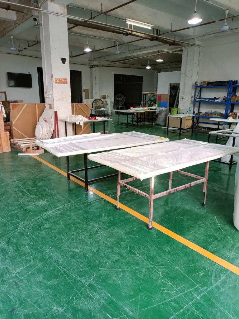 Workers processing marble slabs on a green factory floor with lifting equipment