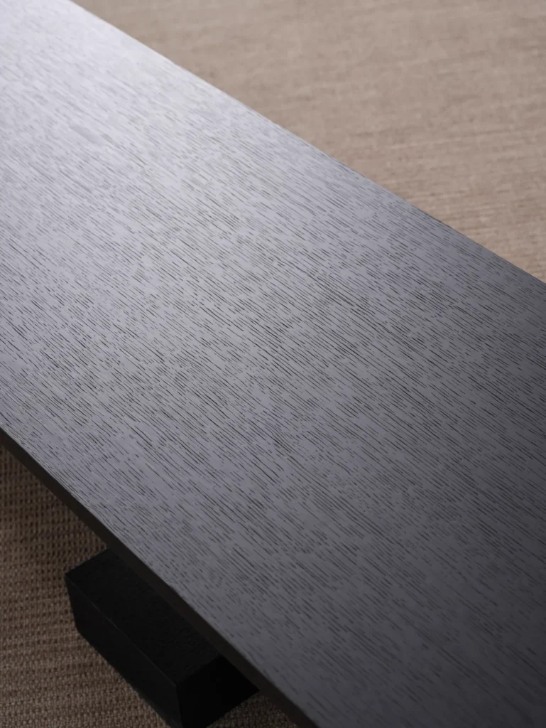 Close-up of a brushed dark metal surface sample with a fine grain