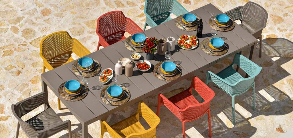 Outdoor dining set with a long table and coloured chairs at the HOWVIN Louvre showroom in Lecong, Foshan
