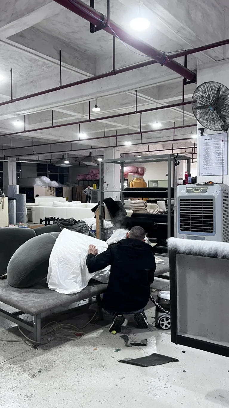 Upholsterer fitting a cover on a sofa frame in a Foshan factory