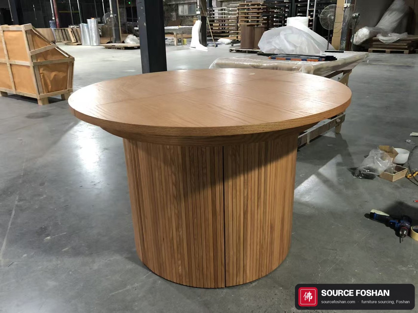 Custom round oak extending dining table, closed, on the factory floor in Foshan before inspection