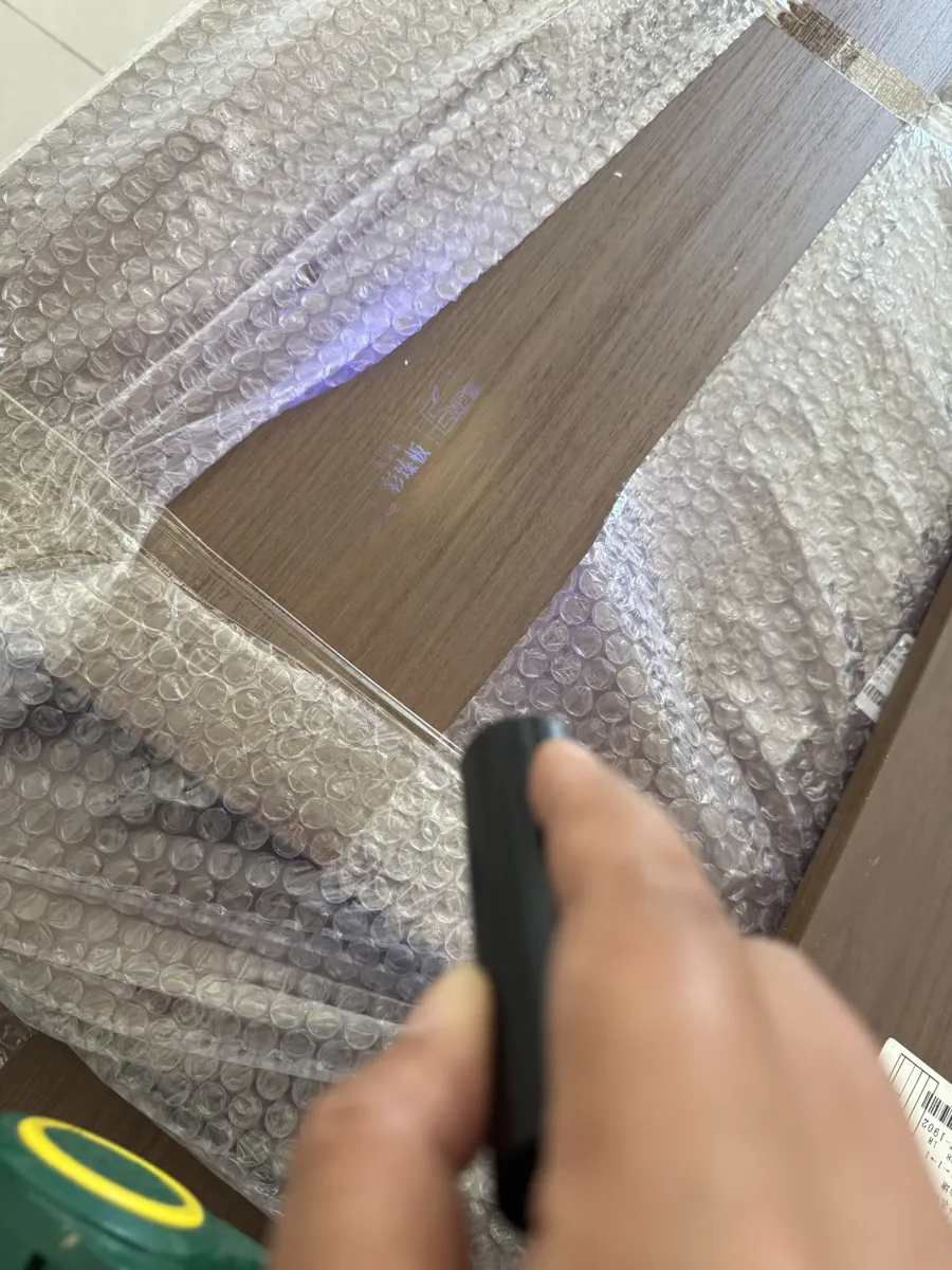 A UV torch reveals the hidden anti-counterfeit watermark printed on the panel surface.