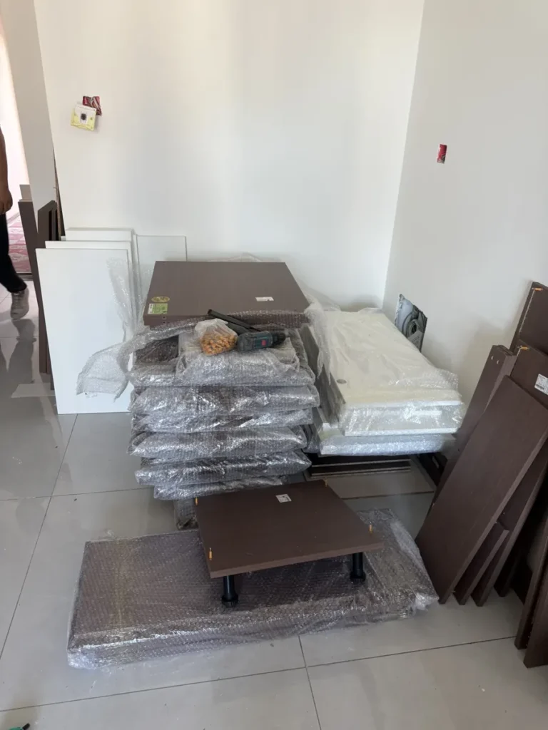 Custom cabinet panels delivered in bubble wrap and stacked in the room, still unopened, while the buyer checks them before installation.