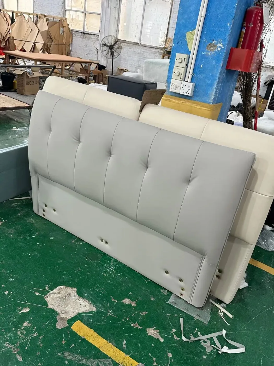 Tufted upholstered headboard standing on a Lecong factory floor before packing