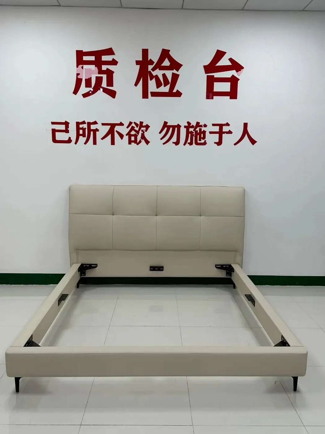 Inspection bench in a Lecong bed factory with a finished upholstered bed frame, under a sign reading QC station