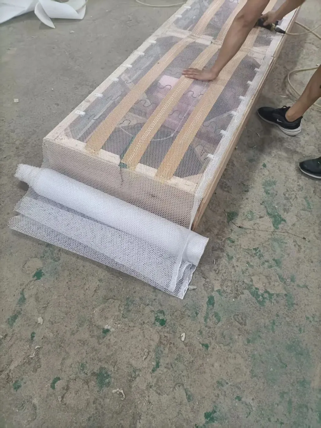 Bed slats being wrapped in protective film on a factory floor
