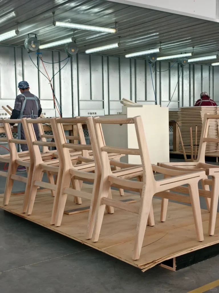 CNC-cut solid timber chair frame components stacked in a woodworking workshop